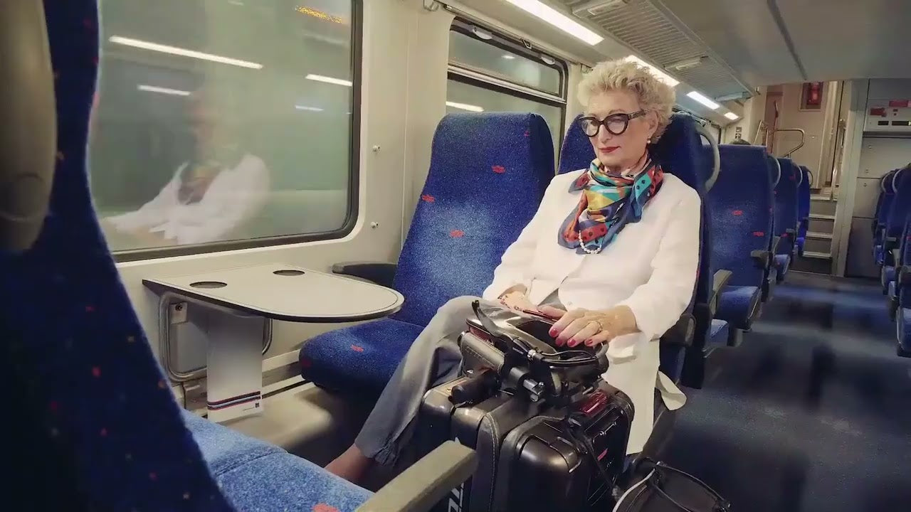 person with mobility issues sitting on a train with a folded mobility scooter next to her